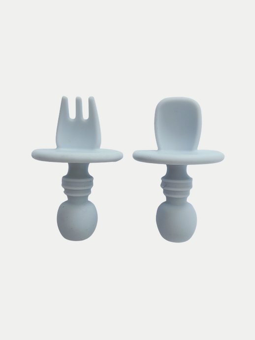 A grey blue silicone spoon and fork utensil set meant for toddlers. The utensils are short and stubby, with a shield to prevent toddlers from inserting the utensil too far into their mouth and gagging on it.
