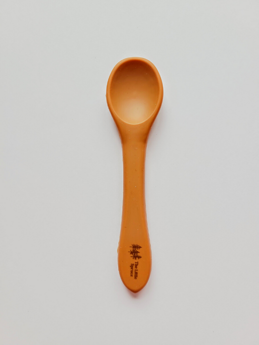 A small burnt orange silicone spoon meant for use by babies and toddlers.  Edit alt text