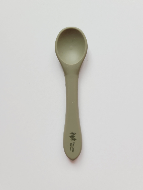 A small sage coloured silicone spoon meant for use by babies and toddlers.