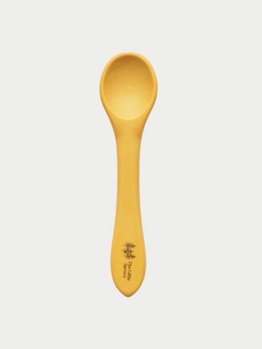 A small mustard yellow silicone spoon meant for use by babies and toddlers.